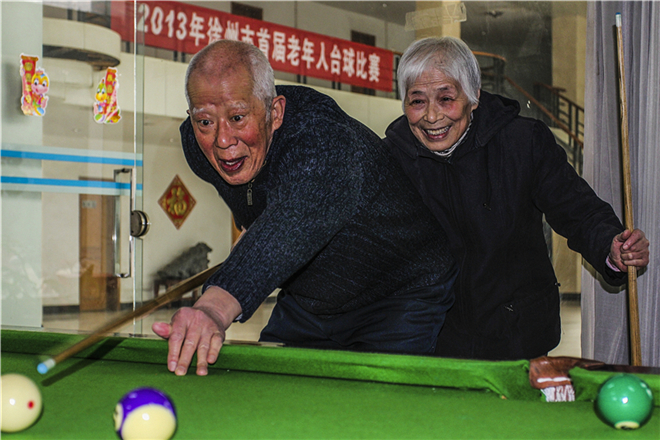 《老夫老妻老球伴》说明：徐州市的一对老夫妻他们在退休后爱上了台球活动，这给他们的晚年生活带来了健康与快乐。图为他们参加徐州市首届老年台球比赛时的一个瞬间。.jpg